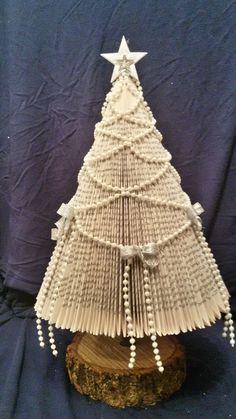 an origami christmas tree made out of books is displayed on a wooden stand