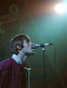 a young man singing into a microphone on stage