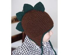 a small child wearing a knitted hat with green leaves on the brim and ears