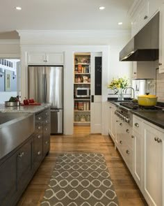 a kitchen with white cabinets and stainless steel appliances, along with a rug on the floor