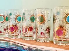 several glasses are lined up on a table with the sun and moon painted on them