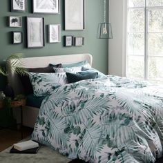 a bed in a bedroom with green walls and pictures on the wall above it,