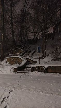 a snow covered road with steps leading up to it and trees in the back ground