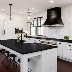 a large kitchen with white cabinets and black counter tops, along with an island in the middle