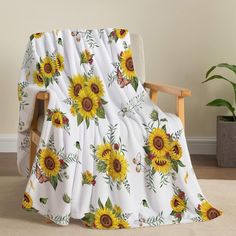 a white blanket with sunflowers on it sitting in front of a wooden chair