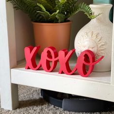 the word xoxo spelled out on a shelf next to a potted plant