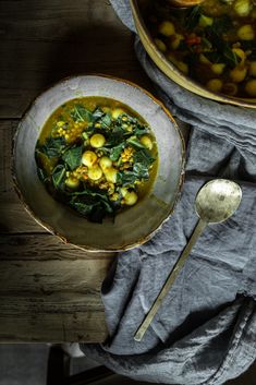 a bowl filled with soup next to a spoon on top of a cloth covered table