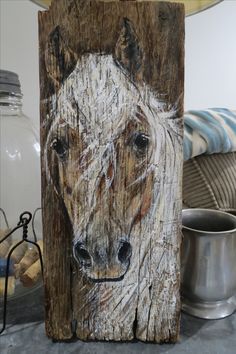 a wooden sign with a horse painted on it's face next to other items