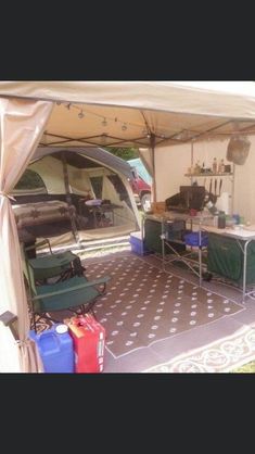 the inside of a tent with tables, chairs and other items in front of it