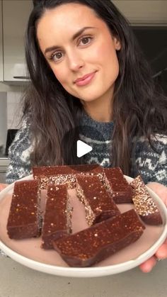 a woman holding a plate with chocolate squares on it