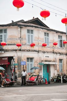 two people standing in front of a building with red lanterns