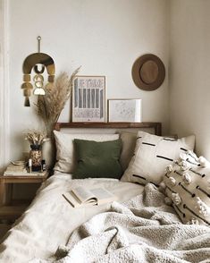 an unmade bed with white sheets, pillows and pictures on the wall above it