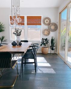 the dining room table is surrounded by black chairs and potted plants in vases