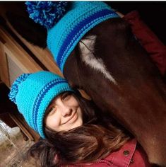 a woman in a blue hat is next to a brown horse