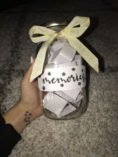 a person holding up a jar filled with marshmallows and the words memories written on it