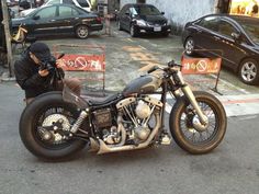 a motorcycle parked on the side of a road next to a parking lot with cars