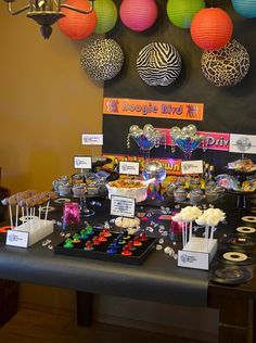 a table topped with lots of desserts and candies on top of black tables