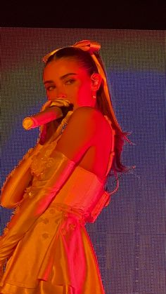 a woman in a yellow dress singing into a microphone