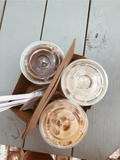 three empty glasses sitting on top of a wooden table next to paper straws and cups