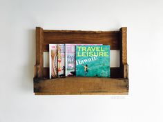 there is a wooden shelf with books on it and magazines in the bottom half,