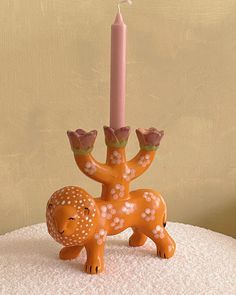 a small candle holder with a deer figurine holding a lit candle on top