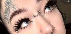 a woman with piercings on her face and eyes