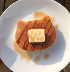 a white plate topped with a piece of cake covered in butter on top of it