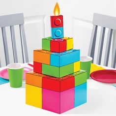 a birthday cake made out of blocks on top of a table with plates and cups