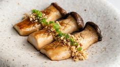 three pieces of food on a white plate with some garnish and green leaves