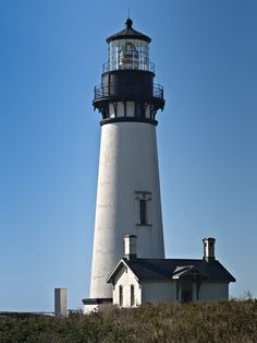 a lighthouse on top of a hill with clouds in the sky above it and grass below