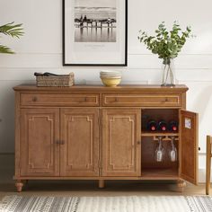 a wooden cabinet with two wine glasses on it and a vase filled with flowers next to it