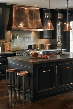 a kitchen with black cabinets and an island in the middle is lit by pendant lights