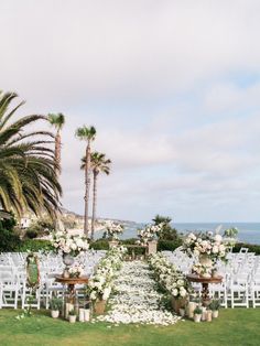 an outdoor wedding setup with white flowers and greenery on the lawn next to the ocean