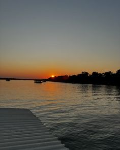 the sun is setting over water with boats in it