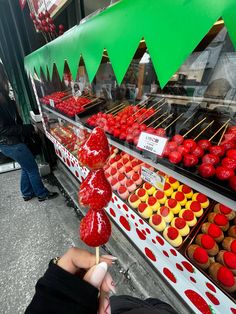 a person is holding up a candy lollipop in front of a display case