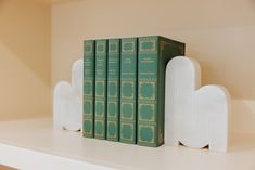 a row of books sitting on top of a white shelf next to two green bookends