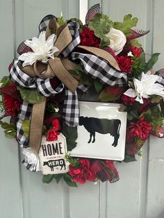 a wreath that is hanging on the front door with flowers and ribbon around it's edges