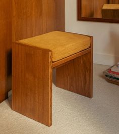 a wooden chair sitting in front of a mirror next to a book shelf and dresser