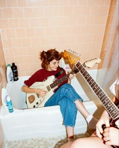 a woman sitting in a bathtub playing an electric guitar