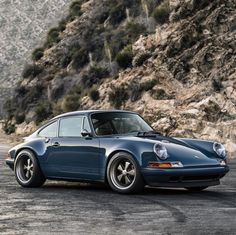 a blue porsche parked in front of a mountain