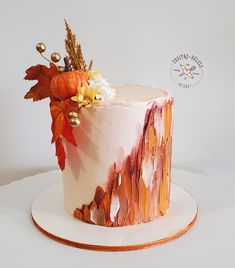 a cake decorated with leaves and flowers on top of a white plate, sitting on a table