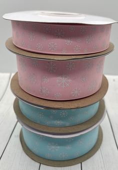 five rolls of pink and blue ribbon on top of each other with snowflakes