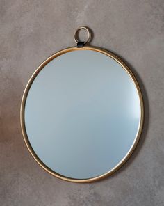 a round mirror hanging on the wall with a ring around it's edge,