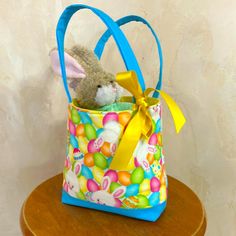 a stuffed animal in a colorful bag on top of a wooden table next to a wall