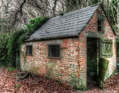 an old brick building in the woods with ivy growing on it's roof and windows