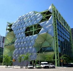 a large green building with lots of windows on it's side in the middle of a city