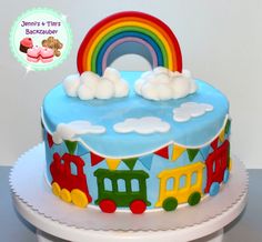 a birthday cake decorated with trains and rainbows