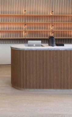 an office desk with a laptop on it in front of a wall made of metal slats