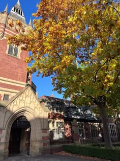 an old brick building with a clock tower on it's side and trees in the foreground