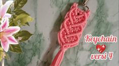 a pink crocheted keychain hanging from a hook on a marble surface